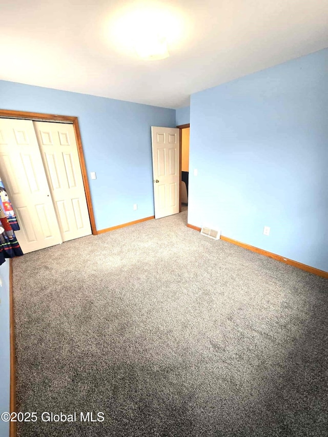 unfurnished bedroom with carpet flooring, baseboards, visible vents, and a closet
