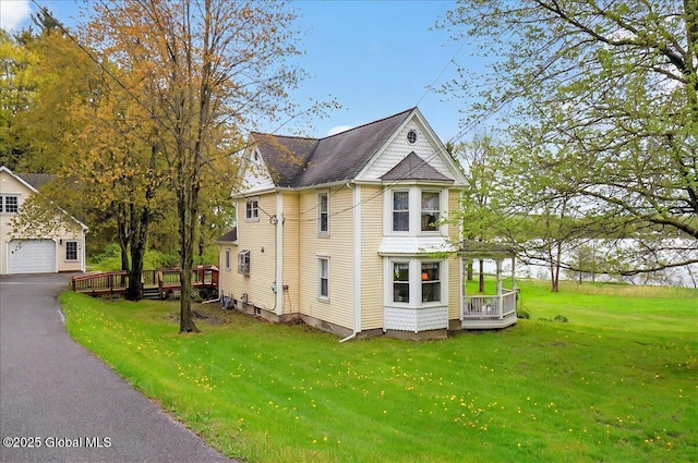 view of side of home with an outbuilding, a deck, a garage, and a yard