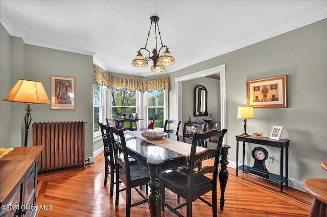 dining room featuring radiator heating unit, baseboards, ornamental molding, wood finished floors, and a chandelier