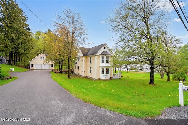 view of property exterior featuring an outbuilding, a lawn, and a detached garage