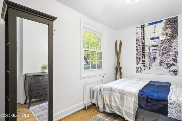 bedroom with baseboards, wood finished floors, and radiator