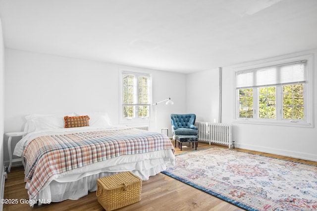 bedroom with radiator heating unit, baseboards, and wood finished floors