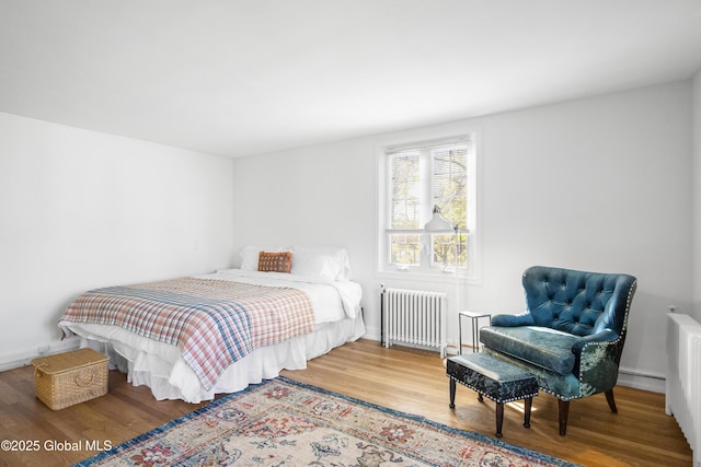 bedroom with radiator, baseboards, and wood finished floors