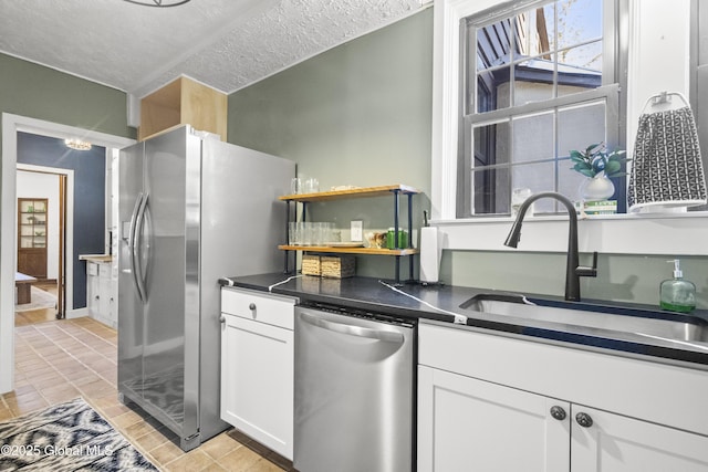 kitchen featuring a sink, a textured ceiling, stainless steel appliances, and white cabinetry