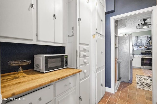 interior space featuring appliances with stainless steel finishes, white cabinets, and wooden counters