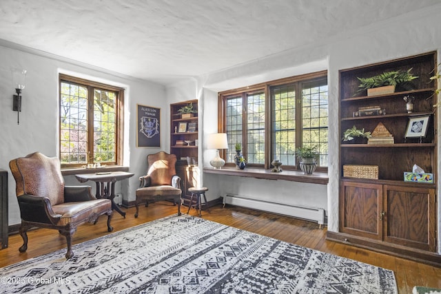 sitting room with crown molding, a baseboard radiator, a healthy amount of sunlight, and hardwood / wood-style flooring