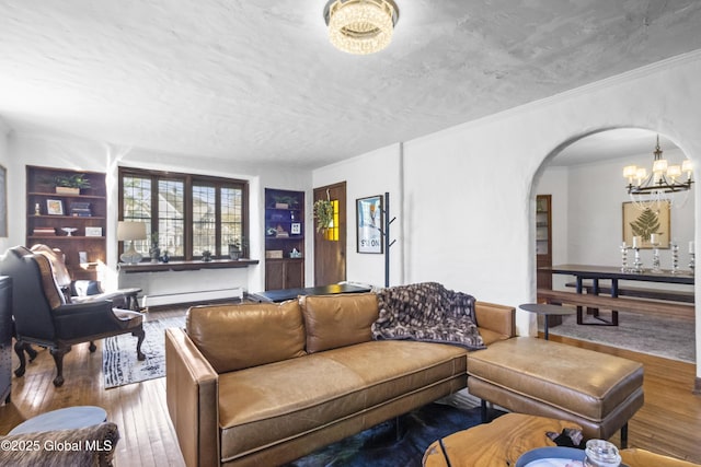 living room featuring wood-type flooring, arched walkways, a chandelier, and baseboard heating