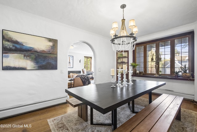 dining area featuring arched walkways, a chandelier, wood finished floors, a baseboard radiator, and ornamental molding