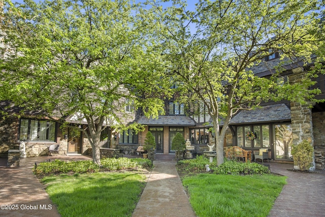 view of front of home featuring stone siding and a front lawn