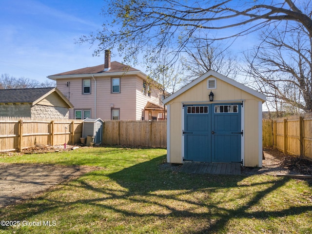 back of house with a lawn, a fenced backyard, a shed, and an outbuilding