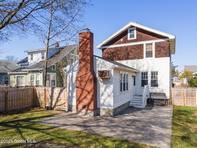 rear view of house featuring a yard, a chimney, a fenced backyard, and a patio area