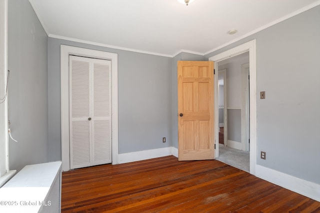 unfurnished bedroom with crown molding, baseboards, a closet, and hardwood / wood-style floors
