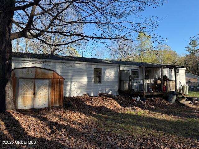 rear view of house featuring an outdoor structure, a storage shed, and a deck