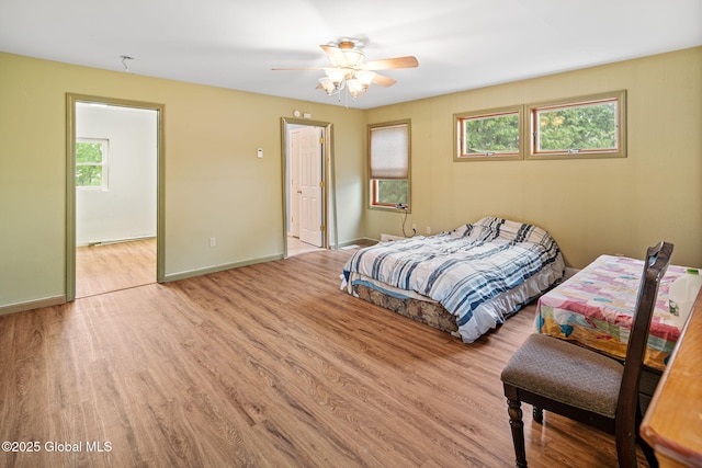 bedroom featuring multiple windows, wood finished floors, baseboards, and ceiling fan