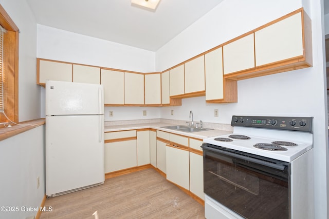kitchen featuring electric range oven, light wood-type flooring, a sink, light countertops, and freestanding refrigerator