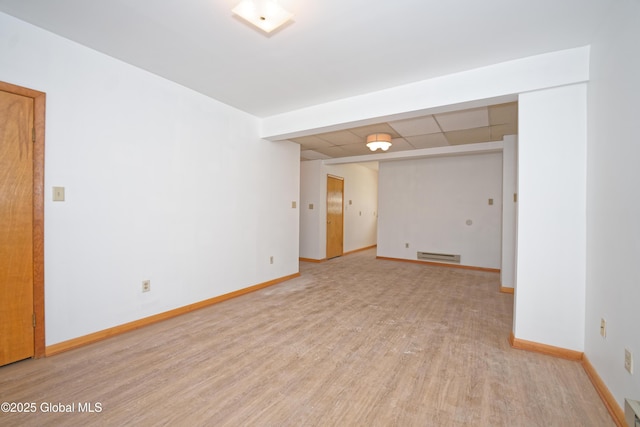 unfurnished room with baseboards, light wood-style flooring, a drop ceiling, and baseboard heating