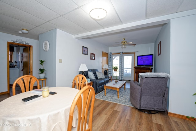 dining area featuring a ceiling fan, washer / dryer, wood finished floors, and a paneled ceiling