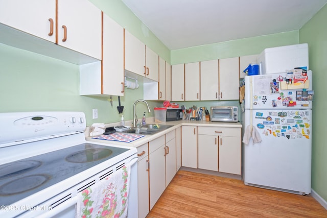 kitchen featuring a sink, white appliances, light countertops, white cabinetry, and light wood-type flooring