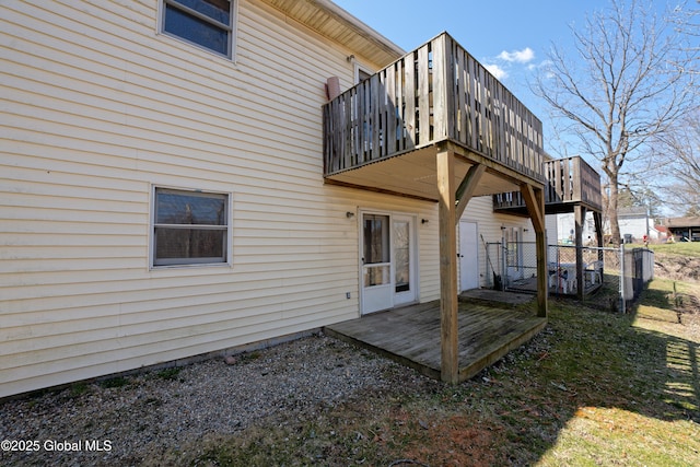 back of property featuring fence, a wooden deck, and a balcony
