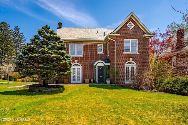 view of front facade with french doors, a front lawn, and brick siding
