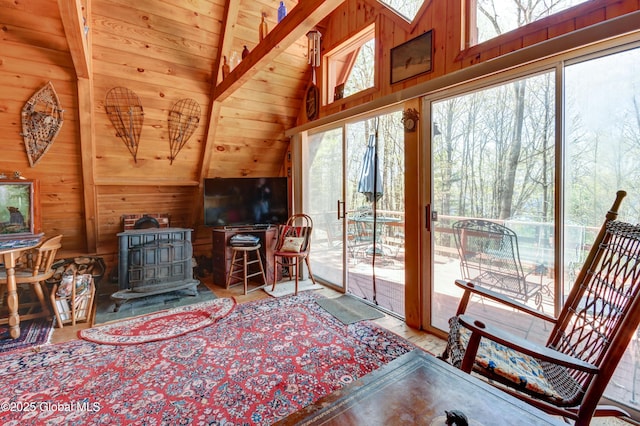 living area featuring vaulted ceiling, wooden ceiling, a wood stove, and wood walls