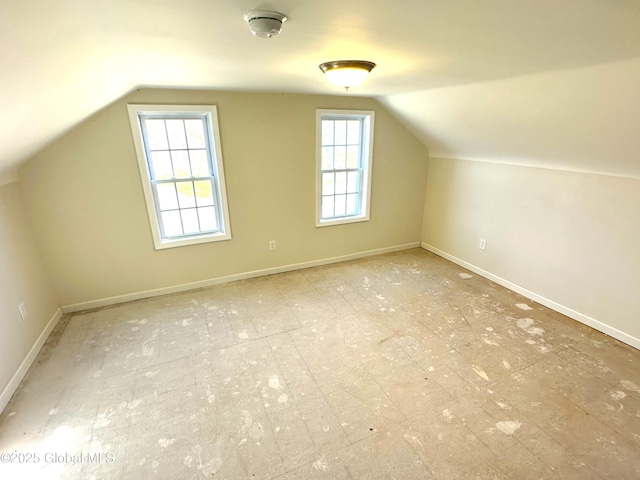 bonus room with lofted ceiling and baseboards