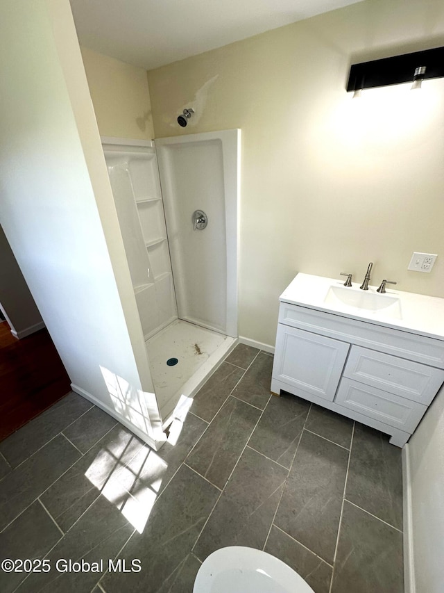 full bath with baseboards, vanity, and a walk in shower