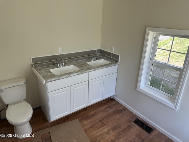 bathroom featuring toilet, visible vents, wood finished floors, and a sink