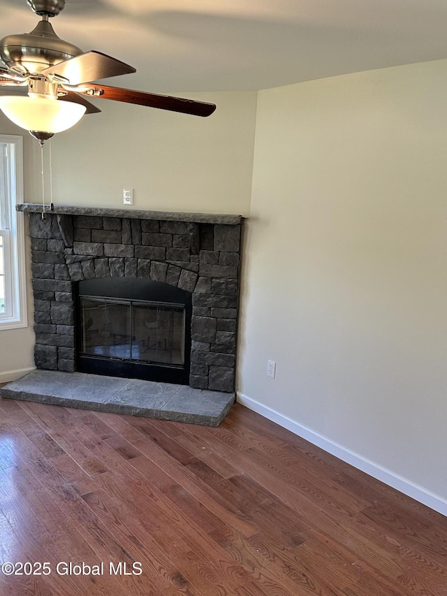 interior details with a fireplace, baseboards, a ceiling fan, and wood finished floors