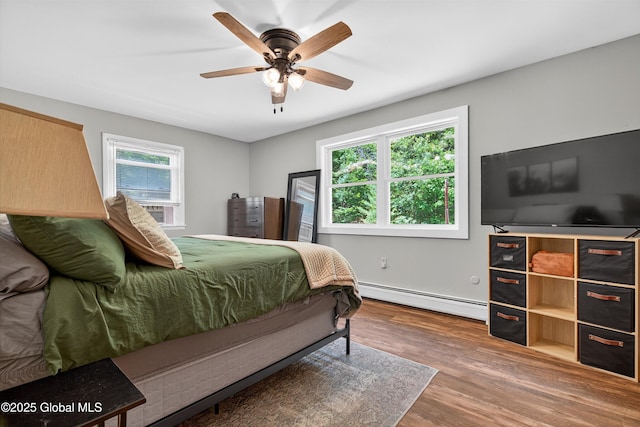 175 Library Ave, Warrensburg, NY 12885 - bedroom featuring baseboard heating, wood finished floors, and a ceiling fan