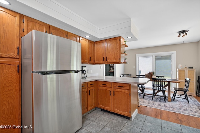 175 Library Ave, Warrensburg, NY 12885 - kitchen with freestanding refrigerator, a peninsula, light countertops, open shelves, and brown cabinetry