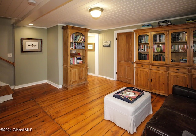 living area with wooden ceiling, baseboards, crown molding, and hardwood / wood-style floors