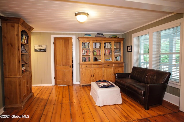 living room with wood-type flooring, ornamental molding, baseboards, and a healthy amount of sunlight