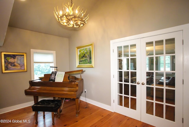living area featuring baseboards, french doors, wood finished floors, and a notable chandelier