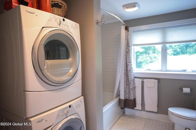 laundry area featuring laundry area, stacked washing maching and dryer, and light tile patterned floors