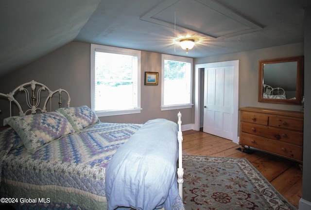 bedroom featuring vaulted ceiling, ceiling fan, attic access, and hardwood / wood-style flooring