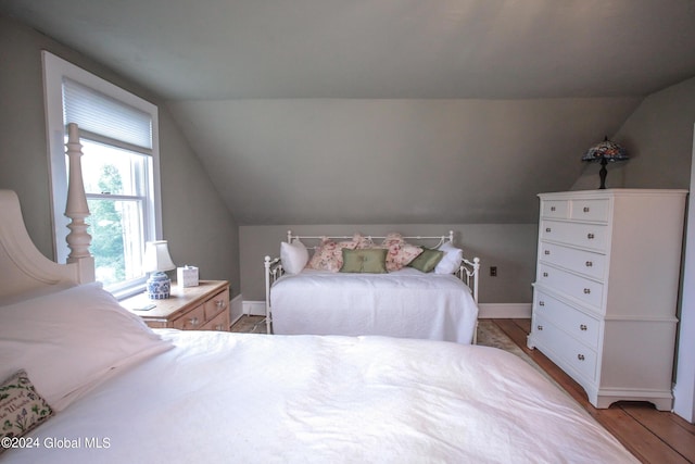 bedroom with baseboards, light wood finished floors, and lofted ceiling