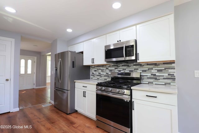 701 Engleman Ave, Glenville, NY 12302 - kitchen featuring stainless steel appliances, light countertops, dark wood-style floors, tasteful backsplash, and white cabinetry