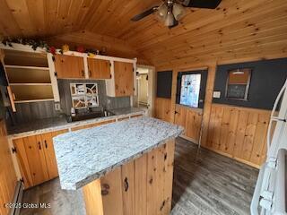 kitchen featuring a ceiling fan, wood walls, wood finished floors, and lofted ceiling