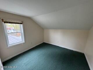 bonus room with baseboards, vaulted ceiling, and dark colored carpet