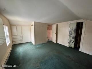additional living space featuring vaulted ceiling and dark colored carpet