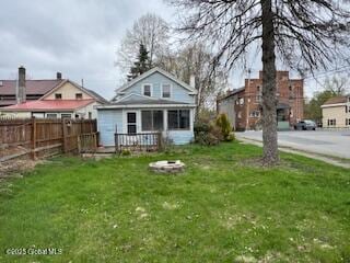 rear view of property featuring a yard, fence, a fire pit, and a wooden deck