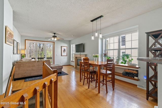 dining room featuring a textured ceiling, plenty of natural light, ceiling fan, and light wood finished floors