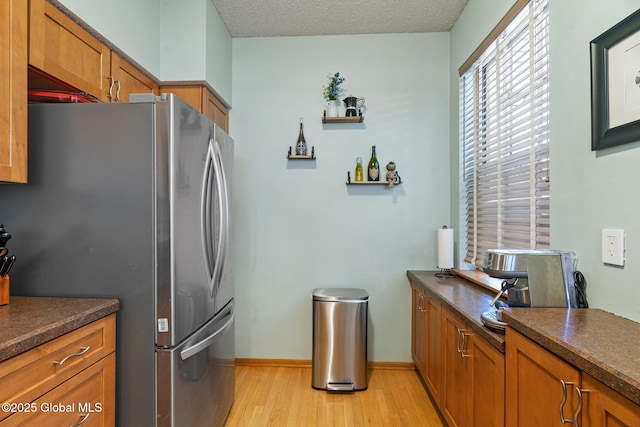 kitchen featuring dark countertops, freestanding refrigerator, and brown cabinets