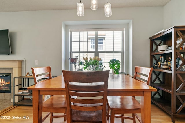 dining room featuring a tiled fireplace and light wood-type flooring