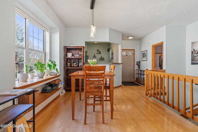 dining space with a textured ceiling and light wood-style flooring