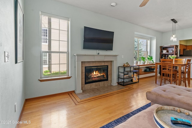 living room featuring baseboards, ceiling fan, wood finished floors, and a fireplace