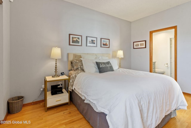 bedroom featuring light wood-style floors, baseboards, and ensuite bath
