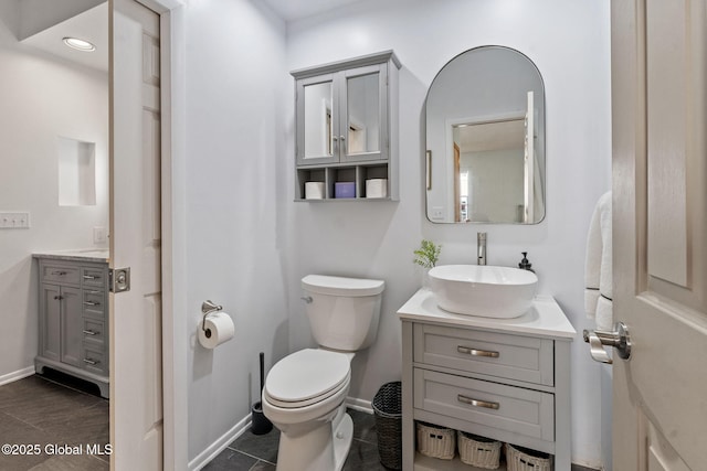 bathroom featuring vanity, baseboards, tile patterned floors, and toilet