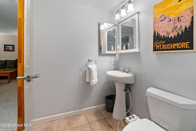 half bathroom featuring baseboards, tile patterned floors, and toilet